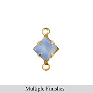 Könnte beinhalten: Ein goldfarbener Verbinder mit einem hellblauen, quadratischen Edelstein in der Mitte. Der Verbinder hat zwei Schlaufen, eine oben und eine unten. Der Text "Multiple Finishes" befindet sich unten.