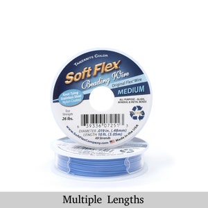 Op de afbeelding: Een spoel blauwe Soft Flex kralendraad in de kleur Tanzanite. De draad is middeldik en is gemaakt van roestvrij staal met een nylon coating. Het etiket geeft aan dat de draad 3,05 meter lang is en een treksterkte van 26 pond heeft.