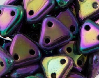 May include: A close-up of a pile of iridescent purple and green triangle-shaped beads with two holes each.