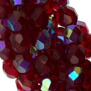 May include: A strand of red iridescent glass beads. The beads are faceted and have a shiny, reflective finish.