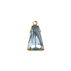 May include: A trapezoidal light blue faceted crystal pendant set in a gold-toned metal prong setting. The pendant features a small circular loop at the top for attachment, showcasing a clear, geometric design with sharp, clean edges and facets.