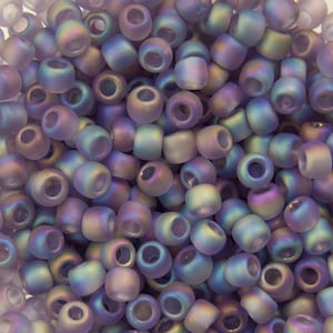 May include: A close-up shot of a pile of iridescent beads. The beads are cylindrical with a hole running through the center. The colors shift from purple to blue to green, creating a shimmering effect. These beads are ideal for jewelry making and crafts.