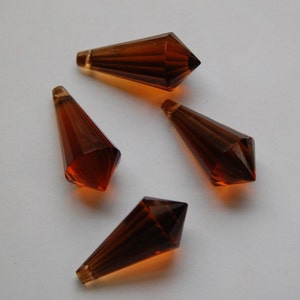 May include: Four brown glass teardrop-shaped crystal prisms with faceted edges.