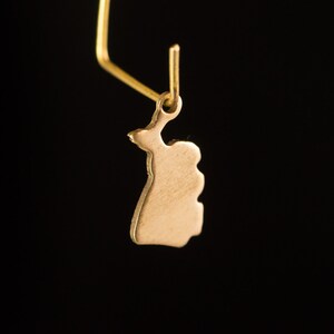 May include: A gold-colored pendant shaped like the outline of Finland. The pendant is hanging from a gold-colored chain.
