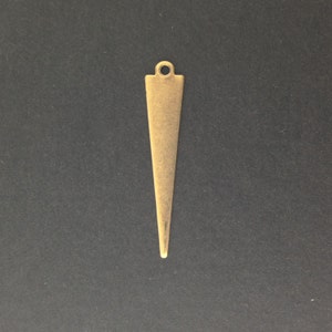 May include: A gold-colored metal pendant shaped like a triangle with a rounded top and a hole for stringing.