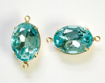 Puede incluir: Dos piedras ovaladas de cristal azul turquesa con engastes de metal dorado y lazos para colgar.