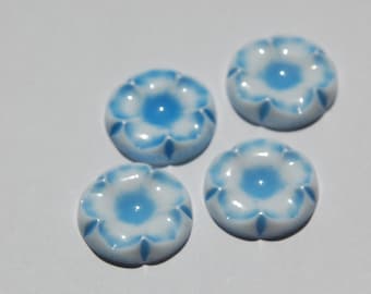 Puede incluir: Cuatro botones de cerámica de color azul y blanco con forma de flor. Los botones tienen un diseño en relieve y un acabado liso y brillante.