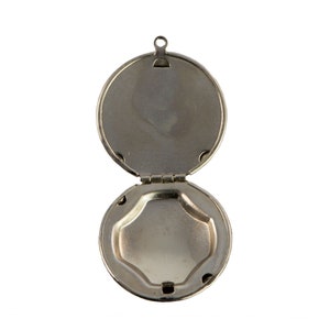 May include: A silver locket with a hinged lid, open to reveal an empty interior. The locket has a simple, round design.