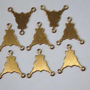 May include: Eight gold-toned metal triangle-shaped charms with three loops each. The charms have a decorative design and are perfect for jewelry making.