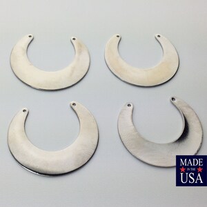 May include: Four silver crescent moon shaped metal charms with two holes each.  The charms are on a white background.  MADE IN THE USA.