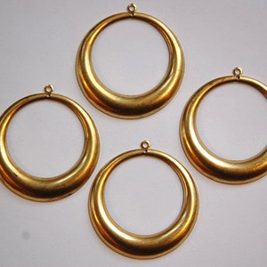 May include: Four gold-colored metal hoops with a rounded edge. Each hoop has a small loop at the top for hanging.