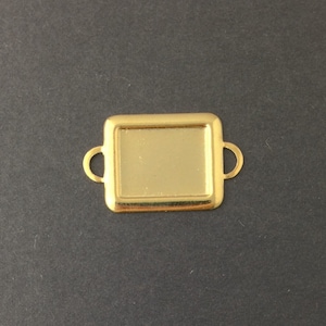 May include: Gold-toned metal tray with two handles. The tray is square shaped and has a raised edge.