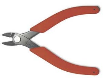 Puede incluir: Cortadores de alambre con mangos rojos y una cuchilla plateada. Los cortadores están diseñados para cortar alambre y objetos pequeños.