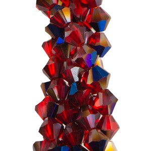 May include: A close-up of a strand of faceted, deep red beads with iridescent highlights. The beads are multi-sided and reflect light, creating a sparkling effect. The beads are strung together, possibly for jewellery making or crafting.