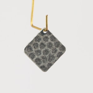 May include: A silver square earring with a hammered texture and a brass hook.