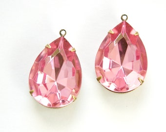 Puede incluir: Dos adornos de cristal de forma de lágrima rosa con engastes de metal dorado. Los cristales tienen un diseño facetado y están listos para ser utilizados para la elaboración de joyas o proyectos de artesanía.