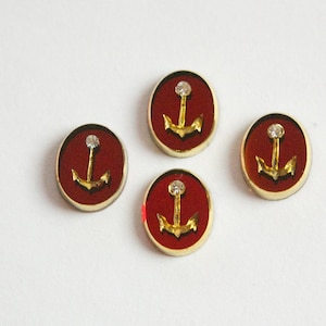 May include: Four red round buttons with gold anchor designs and a single rhinestone in the center of each anchor.