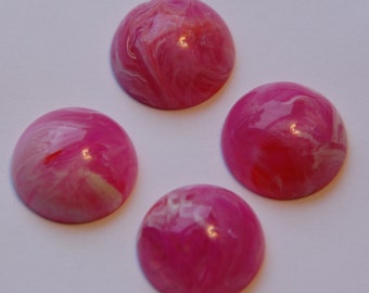 Könnte beinhalten: Vier rosa und weiße marmorierte Cabochons. Die Cabochons sind rund und haben eine glänzende Oberfläche.