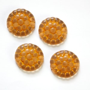 May include: Four round, translucent amber buttons with a raised, textured pattern of small circles.