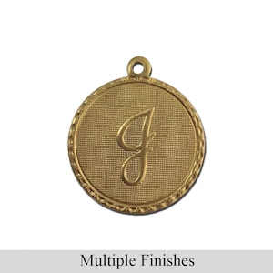 May include: Gold-toned metal charm with a raised letter "J" in a cursive font. The charm is round and has a textured surface.