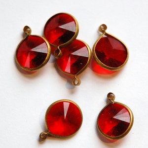 Pode incluir: Seis pingentes redondos de vidro vermelho e metal dourado com design facetado. Os pingentes são redondos e têm um laço na parte superior para pendurar.