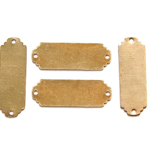 Puede incluir: Cuatro etiquetas de metal de color dorado con bordes decorativos. Las etiquetas están en blanco y tienen dos agujeros en la parte superior.