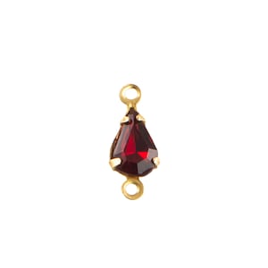May include: A teardrop-shaped, faceted, deep red gemstone pendant with gold-colored metal settings and loops. The pendant is designed for jewelry making, with a classic and elegant aesthetic. The gemstone is a rich, saturated color.