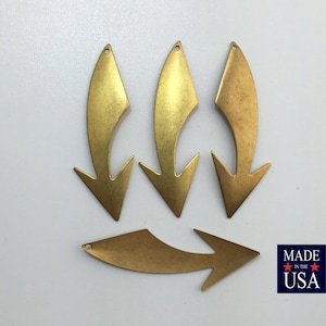 May include: Four brass arrow charms with a hole at the top for hanging. The arrows are all pointing downwards. The charms are made in the USA.
