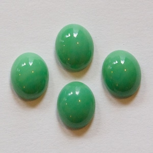 Pode incluir: Quatro pedras preciosas redondas de cabochão verde. As pedras preciosas são lisas e têm um acabamento brilhante.