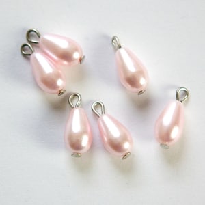 May include: Seven pink pearlescent teardrop-shaped beads with silver loops for hanging.