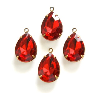 Pode incluir: Quatro pingentes de cristal vermelho em forma de lágrima com engastes de metal dourado. Os pingentes são perfeitos para adicionar um toque de brilho a projetos de joias.