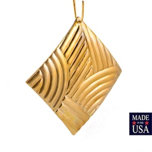 May include: A gold pendant with a geometric design. The pendant is shaped like a diamond and has a textured surface.