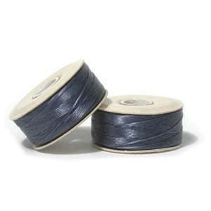 May include: Two spools of dark blue thread, each wound on a beige bobbin.
