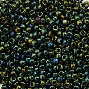 May include: A close-up image of a large quantity of dark green iridescent glass seed beads. The beads are small and round, with a shiny, metallic finish.