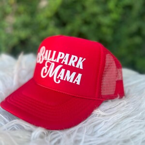Puede incluir: Gorra de camionero roja y blanca con el texto "Ballpark Mama" en letras blancas.
