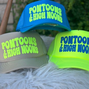 May include: Three trucker hats with the text "PONTOONS & HIGH NOONS" in a retro font. The hats are in blue, grey, and neon yellow.