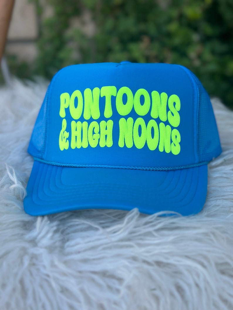 May include: A blue trucker hat with a neon green logo that says "Pontoons & High Noons".