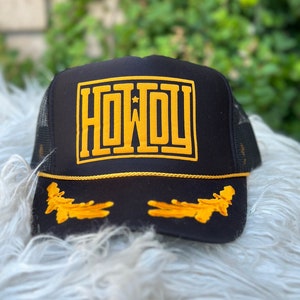 May include: Black trucker hat with a gold embroidered "HOWDY" with a star on the front and gold embroidered leaves on the brim.