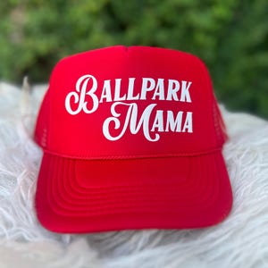 Puede incluir: Gorra de camionero roja con un logotipo bordado en blanco que dice "Ballpark Mama".