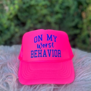 May include: A bright pink trucker hat with a blue embroidered message that reads "On My Worst Behavior".