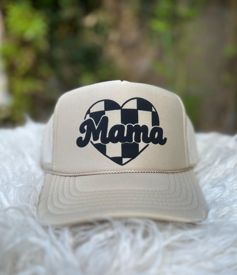 May include: A beige trucker hat with a black and white chequered heart and the word "Mama" in a retro font.