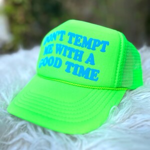 May include: A neon green trucker hat with a yellow brim and a blue inscription that reads "Don't tempt me with a good time".