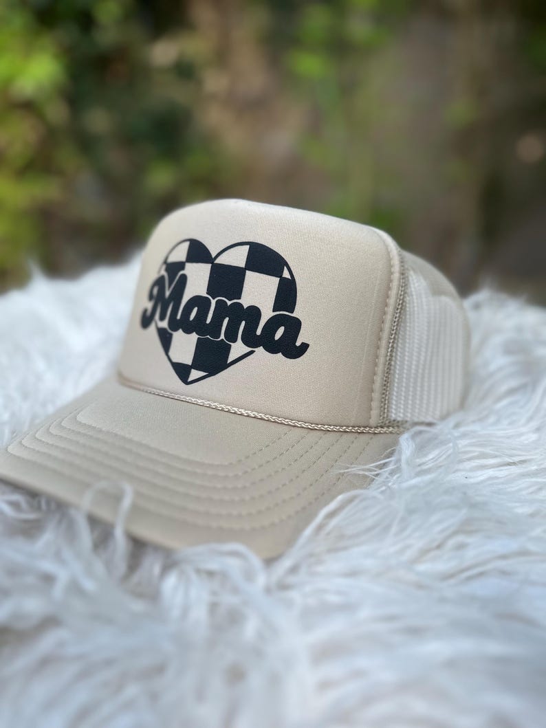 May include: A beige trucker hat with a black and white chequered heart and the word "Mama" in a retro font.