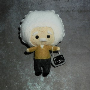 May include: A felt toy of Albert Einstein with white hair, a brown sweater, black pants, and a chalkboard that says "E=mc^2".