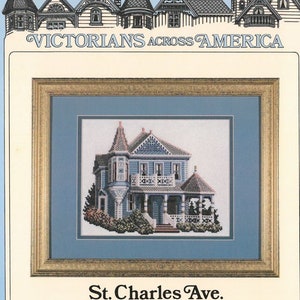 May include: A cross-stitch pattern of a blue Victorian house with white trim and a porch. The house is surrounded by green bushes and flowers. The title "St. Charles Ave. New Orleans, Louisiana" is printed below the image.