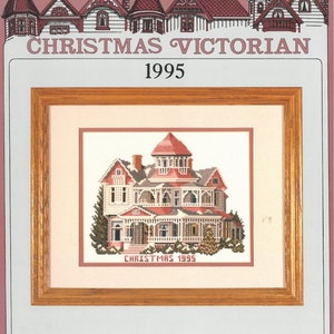 May include: Cross stitch pattern featuring a detailed illustration of a Victorian house decorated for Christmas. The house is pink and white with a red roof and a large porch. The text "Christmas 1995" is printed below the house.