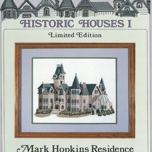 May include: A cross-stitch pattern of a historic house in San Francisco called the Mark Hopkins Residence. The pattern is framed in a brown wood frame and is part of a limited edition series called "Historic Houses I."