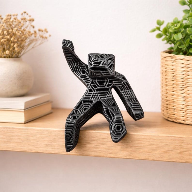 A geometric statue of Dr. Ryland grace created by Rocky in Project Hail Mary resting on the side of a shelf