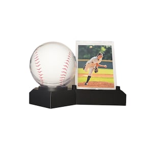 May include: A baseball-themed display featuring a clear baseball with red stitching, mounted on a black base. Next to it is a photo of a baseball player pitching. The display is designed to showcase baseball memorabilia.