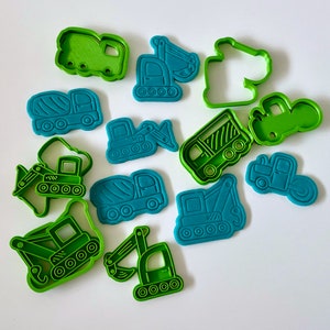 May include: A set of 12 green and blue plastic cookie cutters shaped like construction vehicles, including a cement mixer, bulldozer, excavator, and tipper truck.